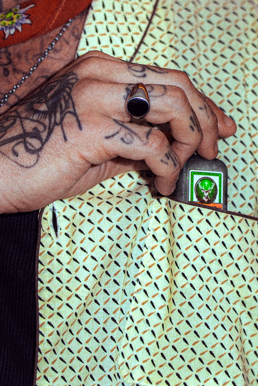 A close-up of a tattooed hand holding a small Jägermeister bottle.